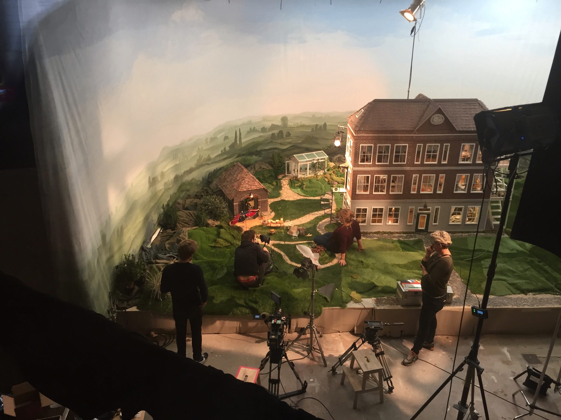 Behind the scenes — overview of the set with crew, cameras and the painted landscape